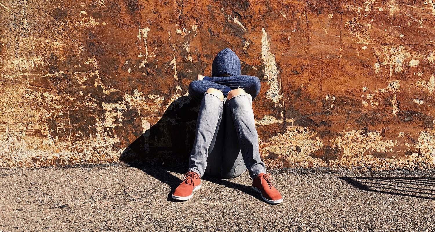 Ungdom sitter lutad mot vägg
